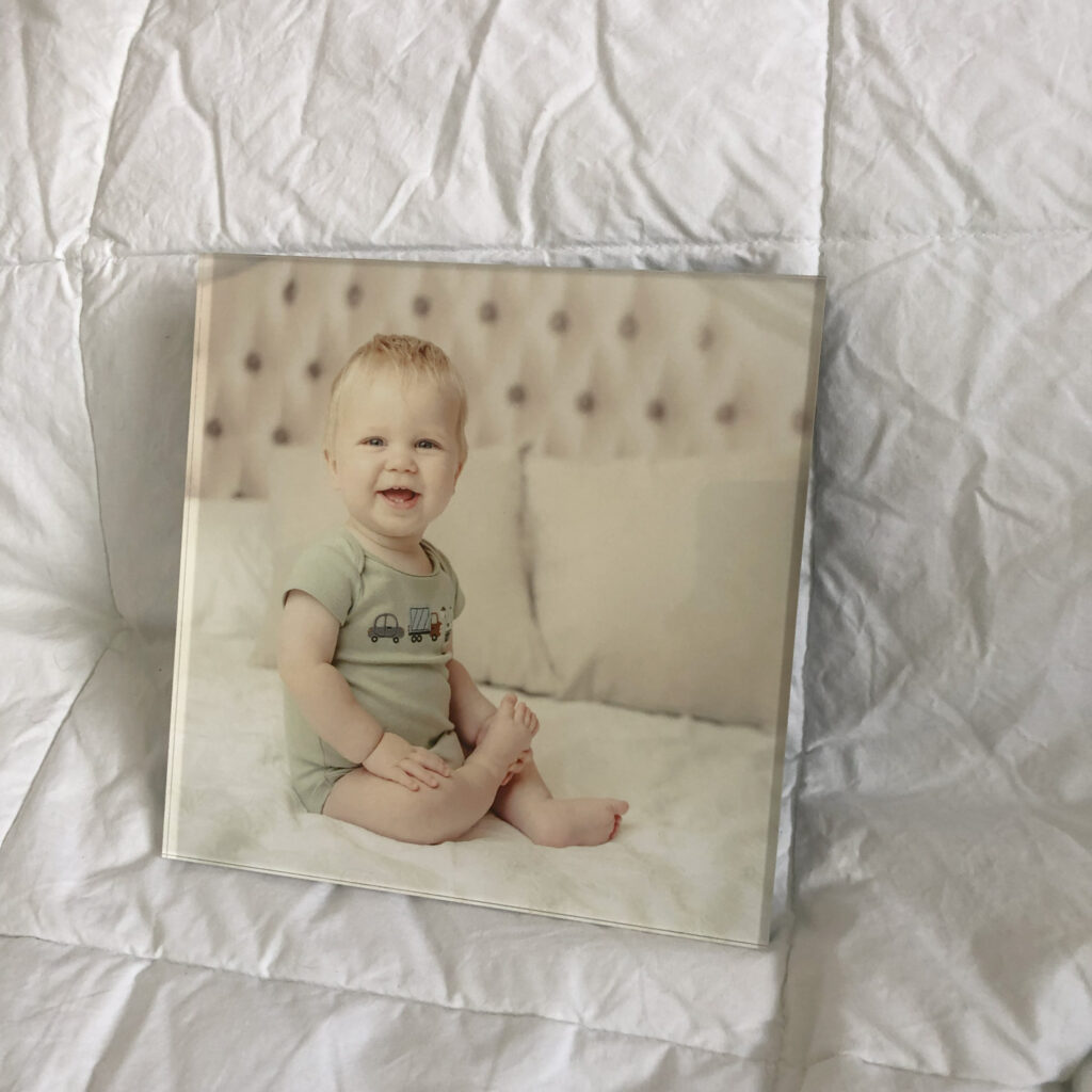 An acrylic block featuring a portrait of a toddler sitting on a bed.