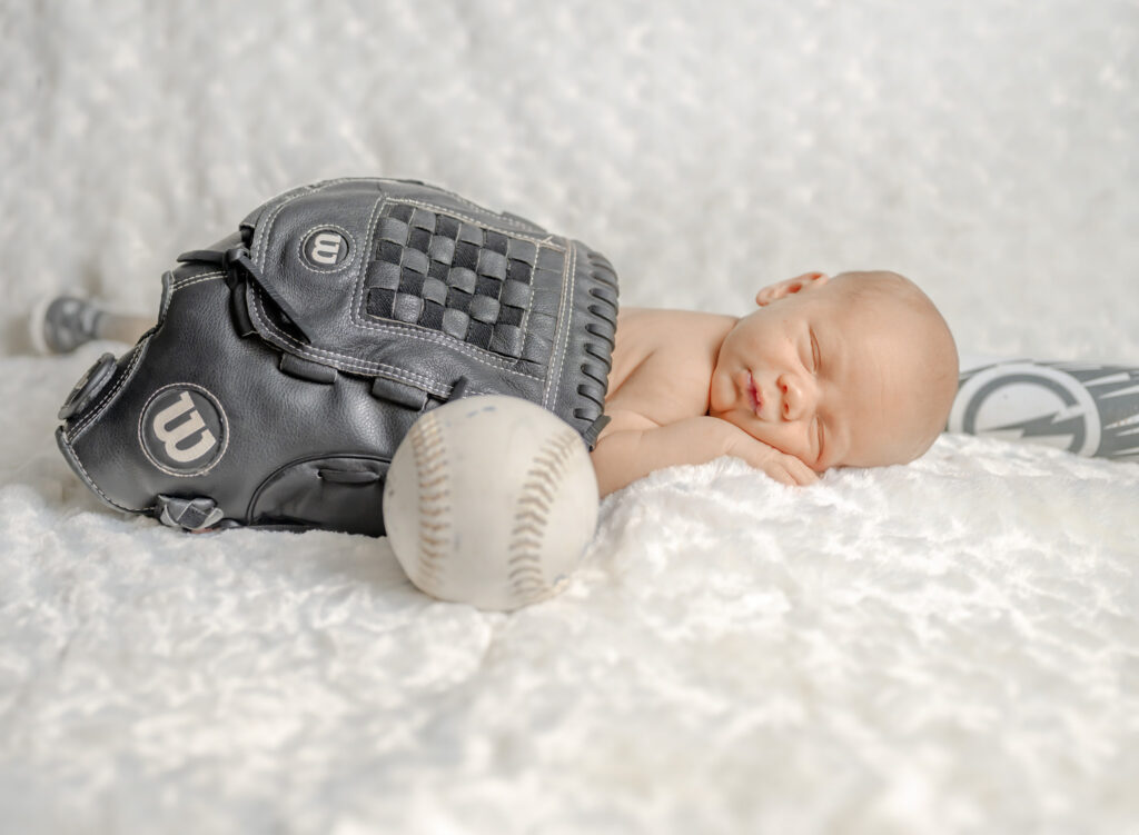 Newborn session featuring a baby snuggled up in a baseball glove.