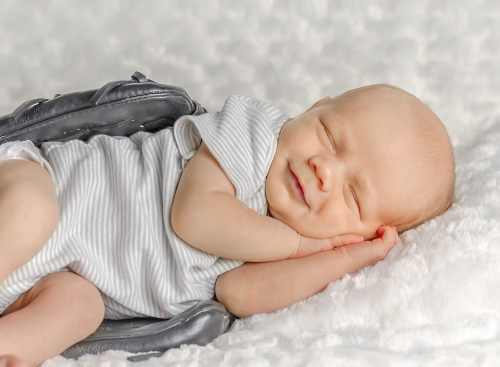 Sleeping newborn boy dressed in neutral tones during Niagara newborn photo session